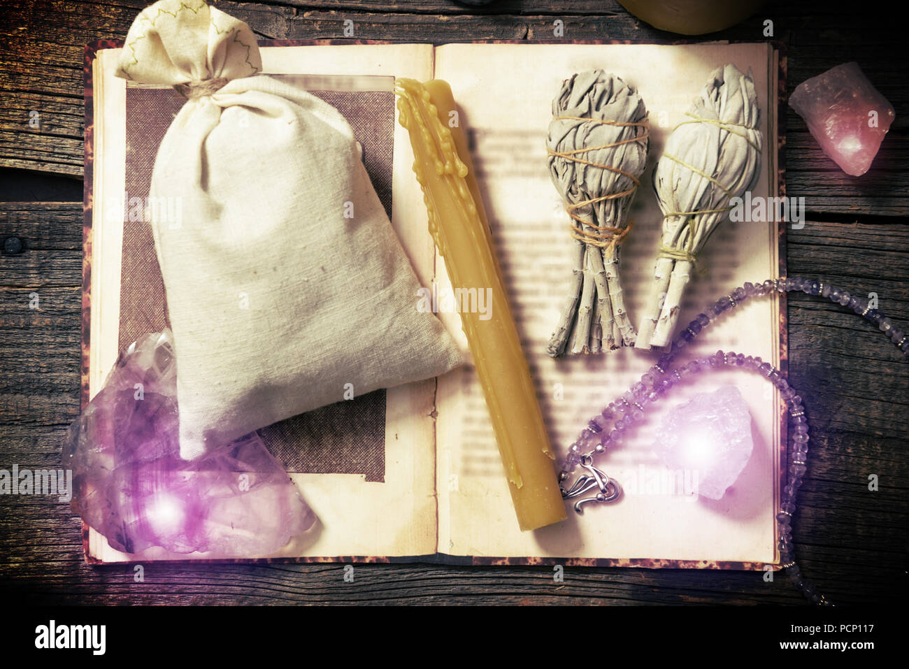 Pierres naturelles, sauge blanche, bougie, sac sur un livre sur planche de bois, la sorcellerie tools Banque D'Images