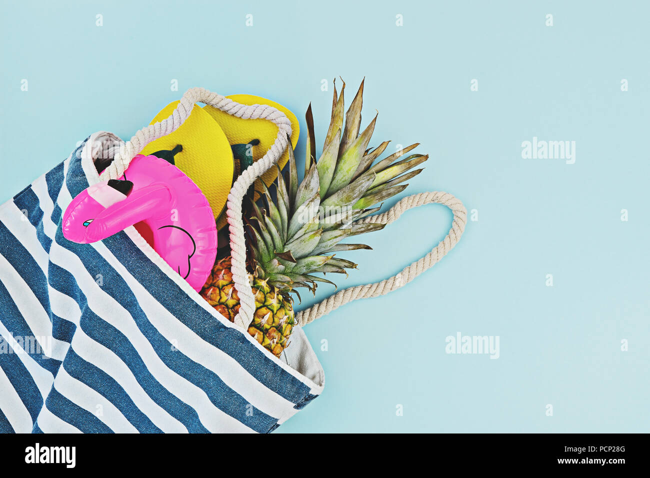 Piscine d'été colorés ou ensemble de plage télévision lay. Flamingo gonflable flottant, les tongs, ananas sur fond bleu, vue de dessus, copiez l'espace. Summertime Banque D'Images