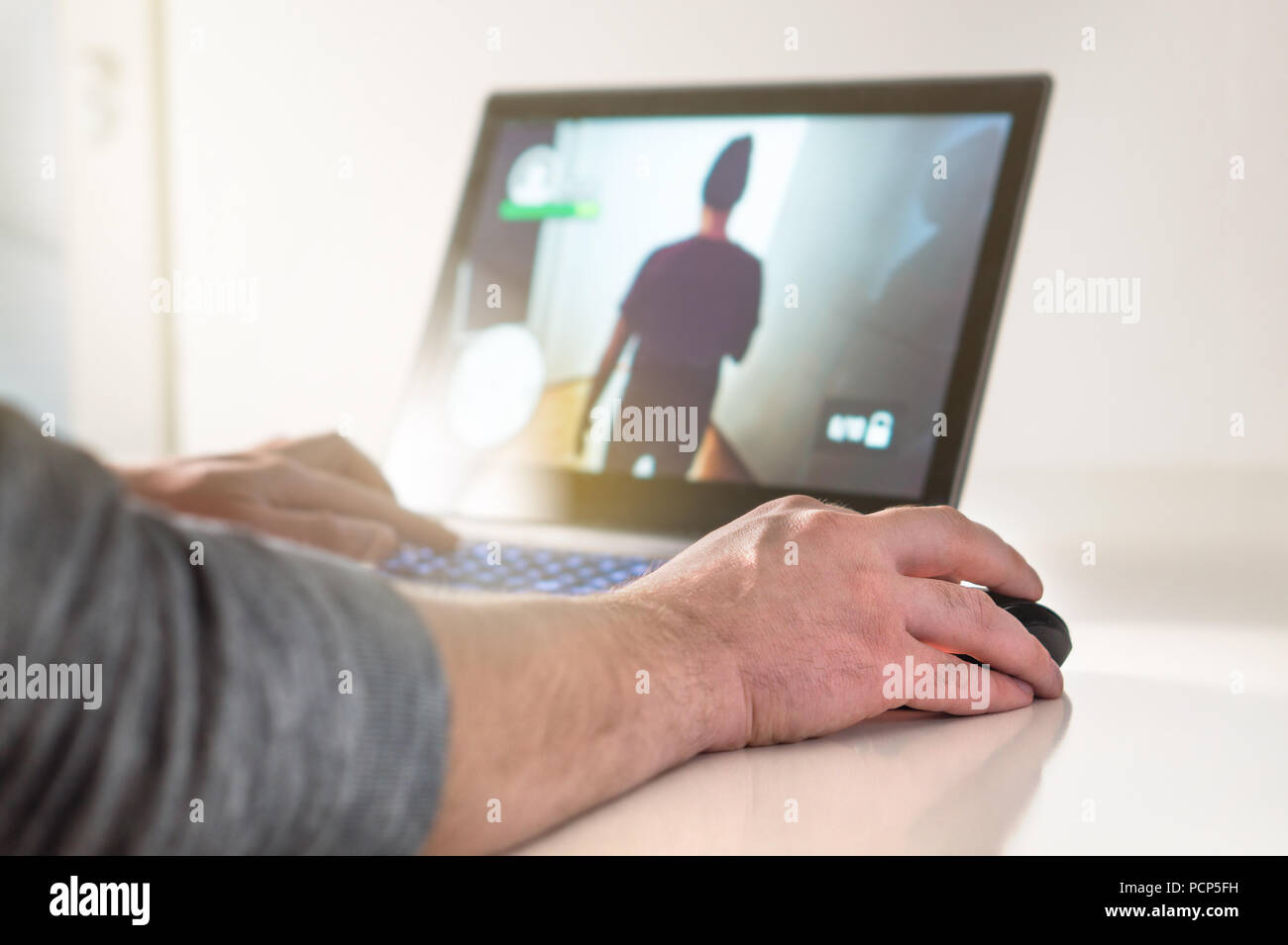 Jouer jeu vidéo avec ordinateur portable. Gamer avec ordinateur. Jeune homme la main sur la souris. Jeux de compétition, electronic sports et loisirs. Banque D'Images