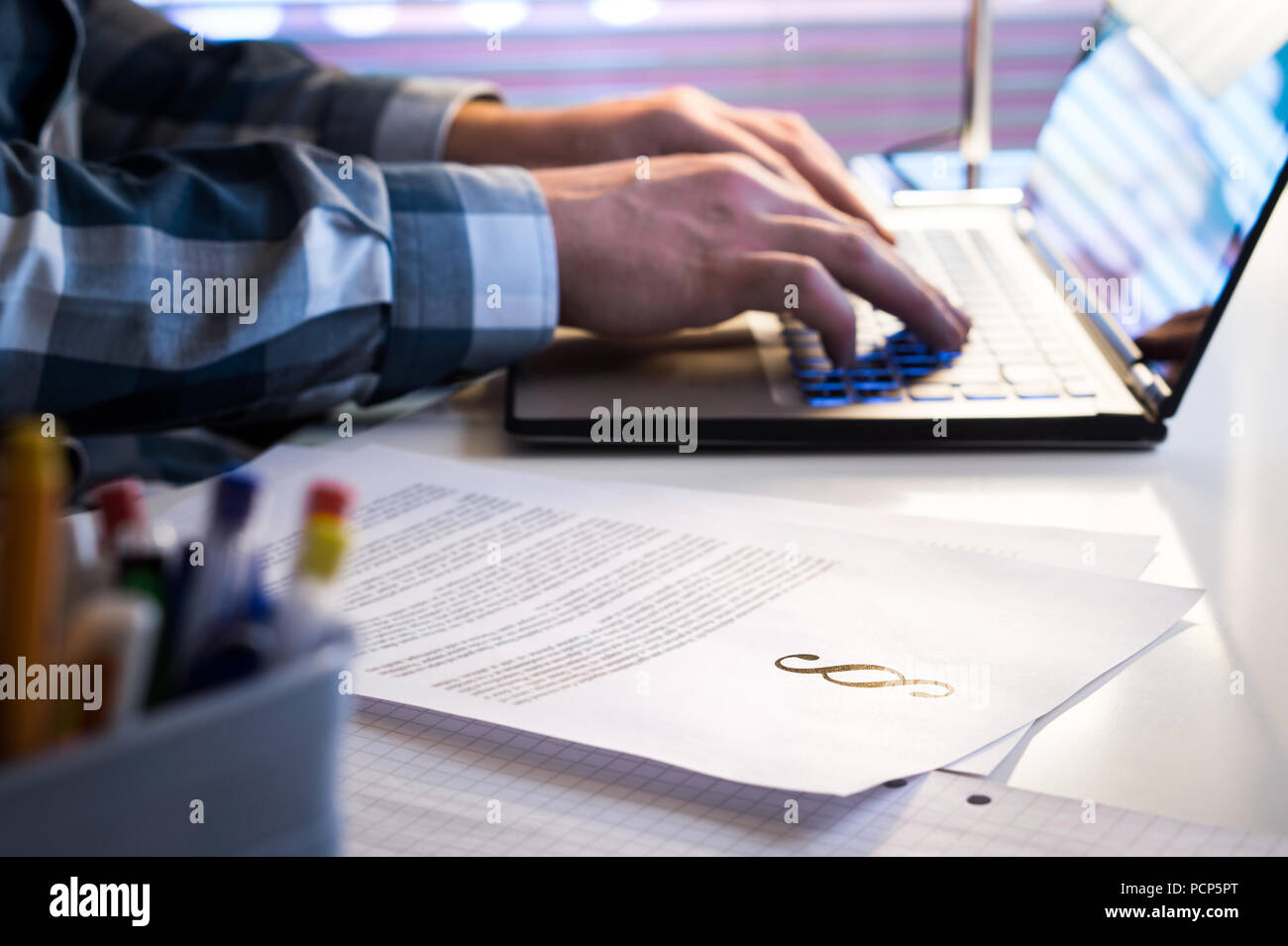 Avocats en exercice tard dans la nuit. Procureur écrit un document juridique avec un ordinateur portable. Morceaux de papier avec symbole de la justice. Banque D'Images