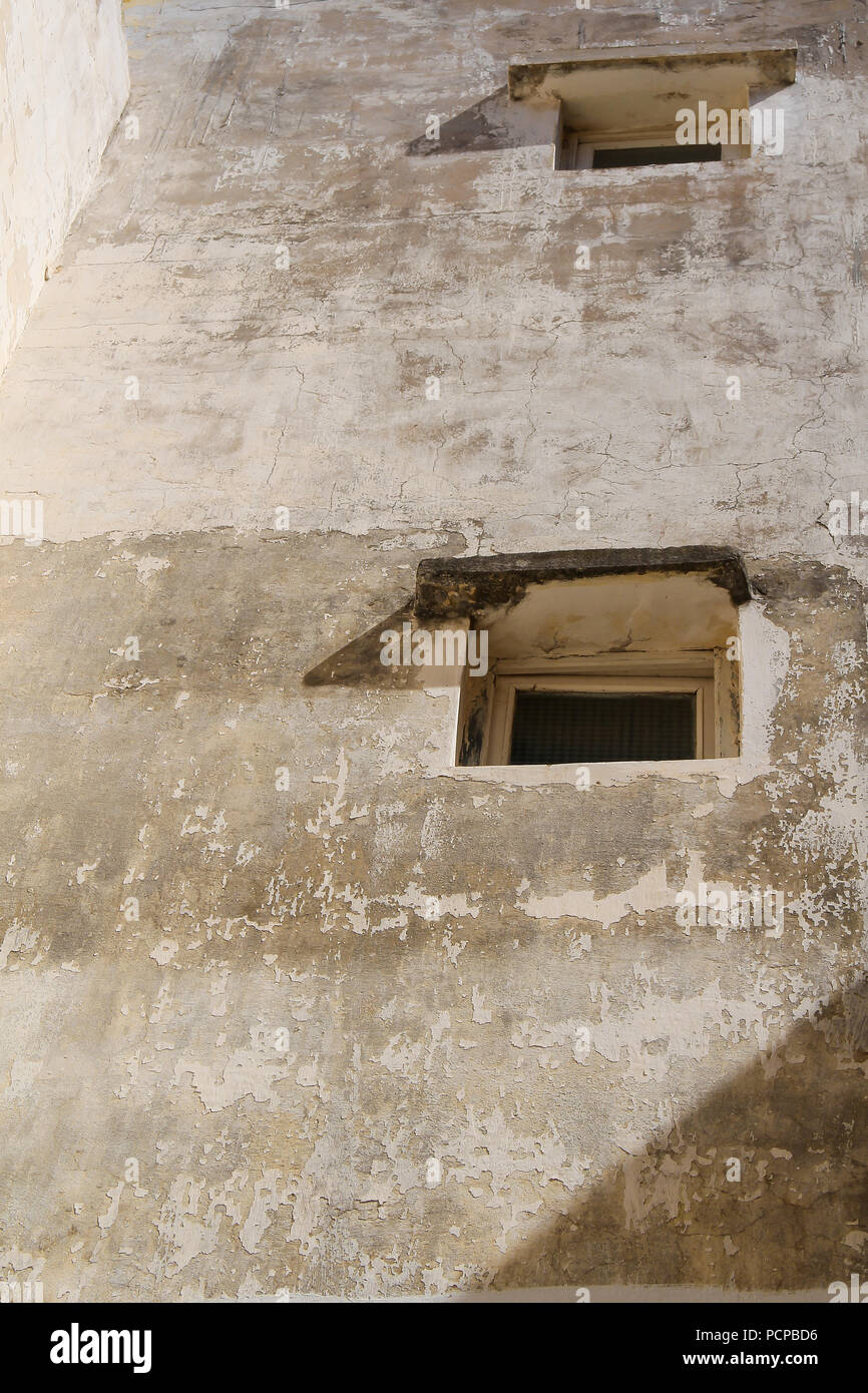 Murs d'une maison traditionnelle avec des petites fenêtres. Façade vieillies. Bâtiments de l'ancienne forteresse portugaise. El Jadida, Maroc. Banque D'Images