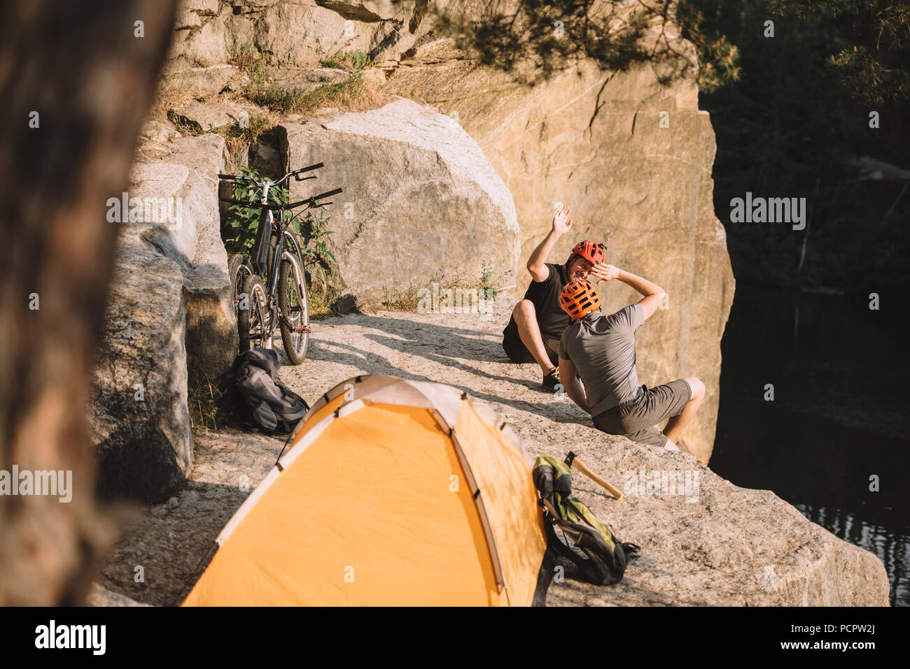 Portrait d'essai active bikers assis sur une falaise rocheuse avec tente de  camping et de donner cinq haut Photo Stock - Alamy