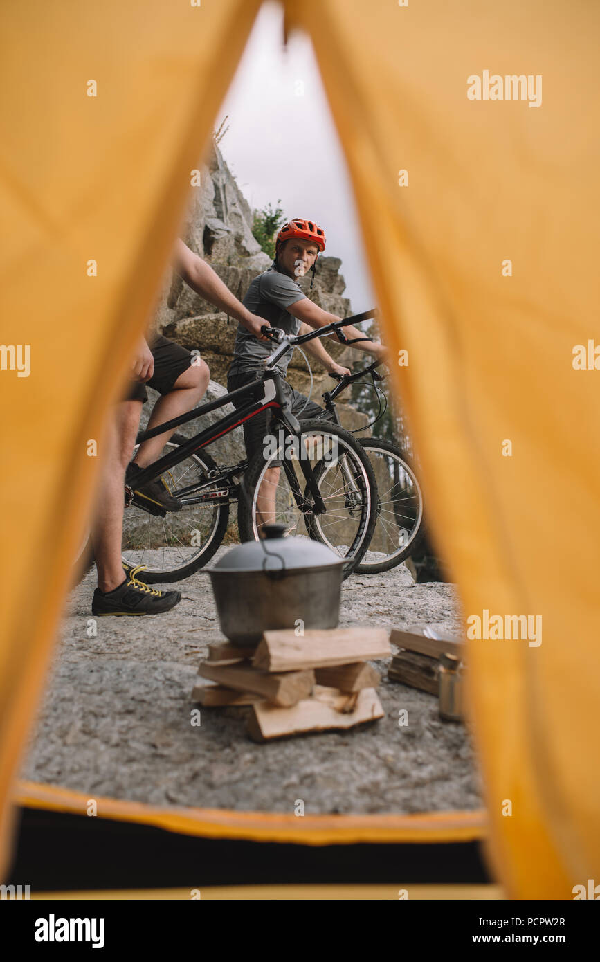 Voir l'essai de bikers sur une falaise rocheuse de l'extérieur à partir de la tente de camping Banque D'Images