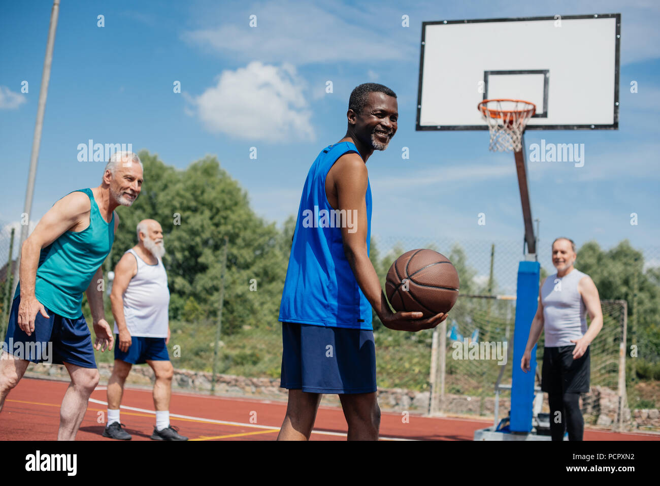 L'interracial personnes âgées sportifs jouant au basket-ball ensemble sur  des jeux pour enfants Photo Stock - Alamy