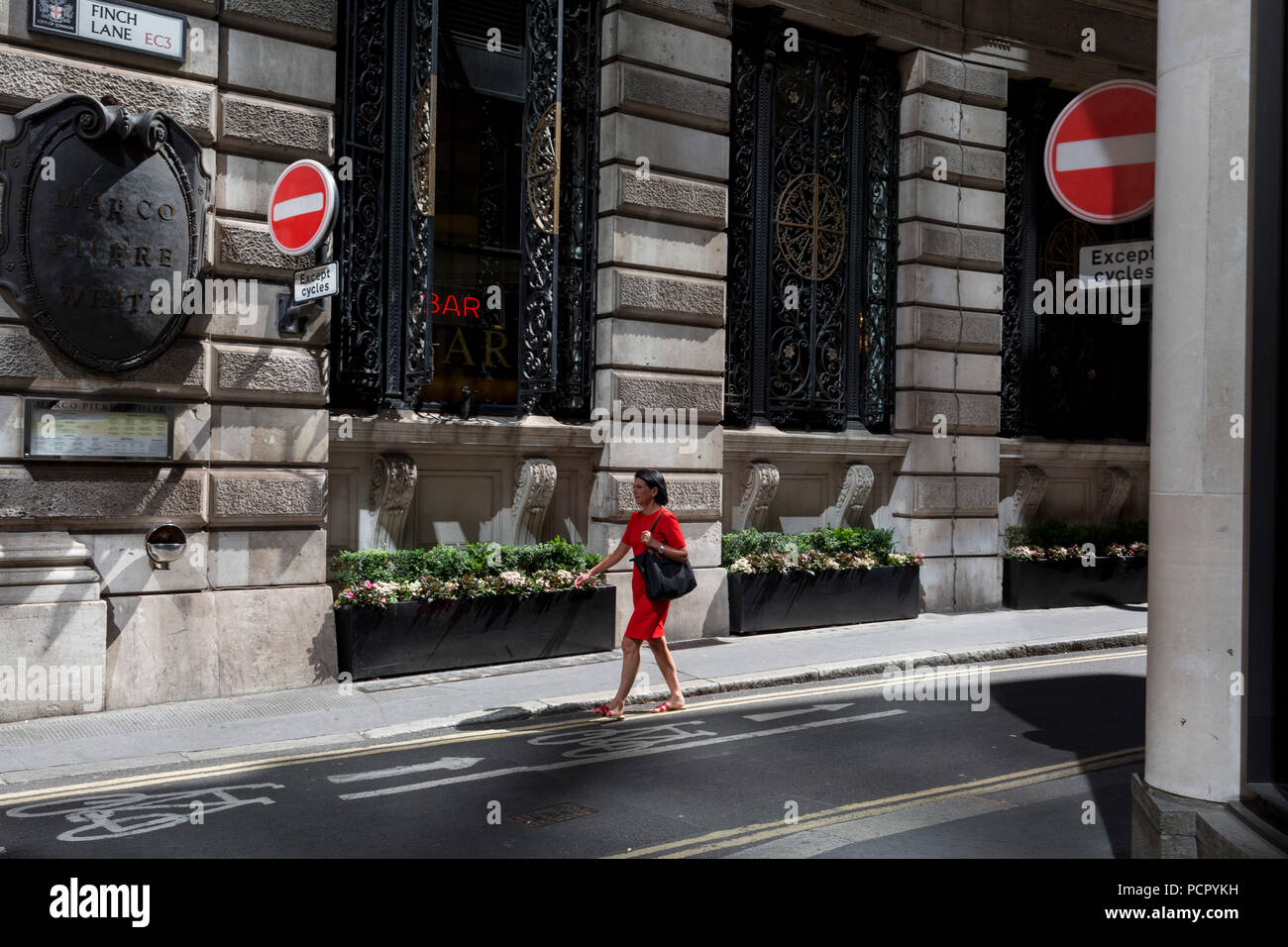 Une dame dans une robe rouge marche sur la rue Finch, un étroit couloir de l'époque médiévale dans la ville de Londres, la capitale historique du quartier financier, le 2 août 2018, à Londres, en Angleterre. Banque D'Images