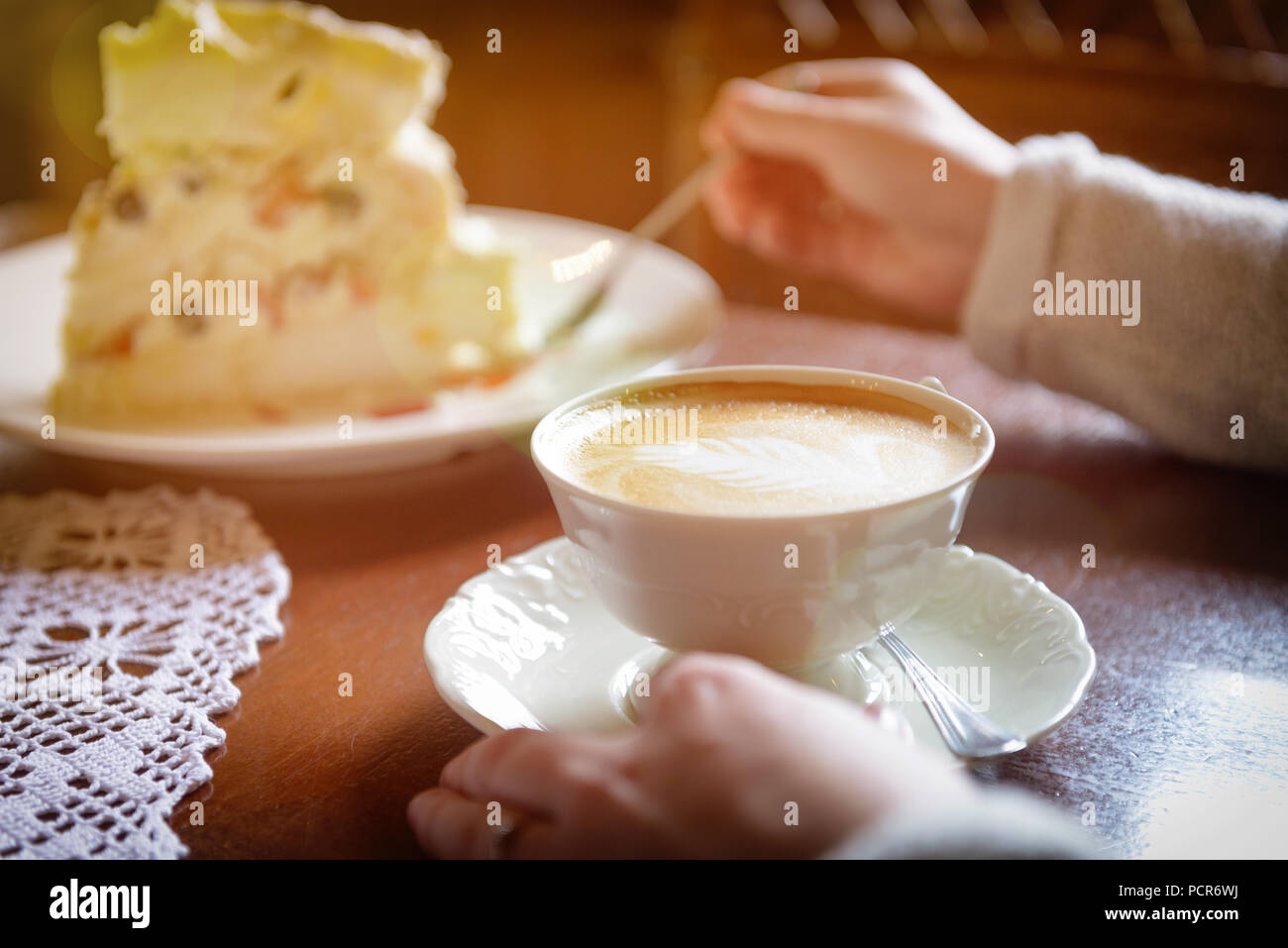 Image authentique de woman's hand holding cappuccino, gâteau à la meringue à l'arrière-plan Banque D'Images