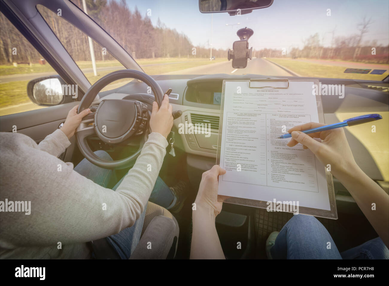 Remplissage de l'examinateur du permis de conduire en forme d'essai routier avec son étudiante assise à l'intérieur d'une voiture Banque D'Images