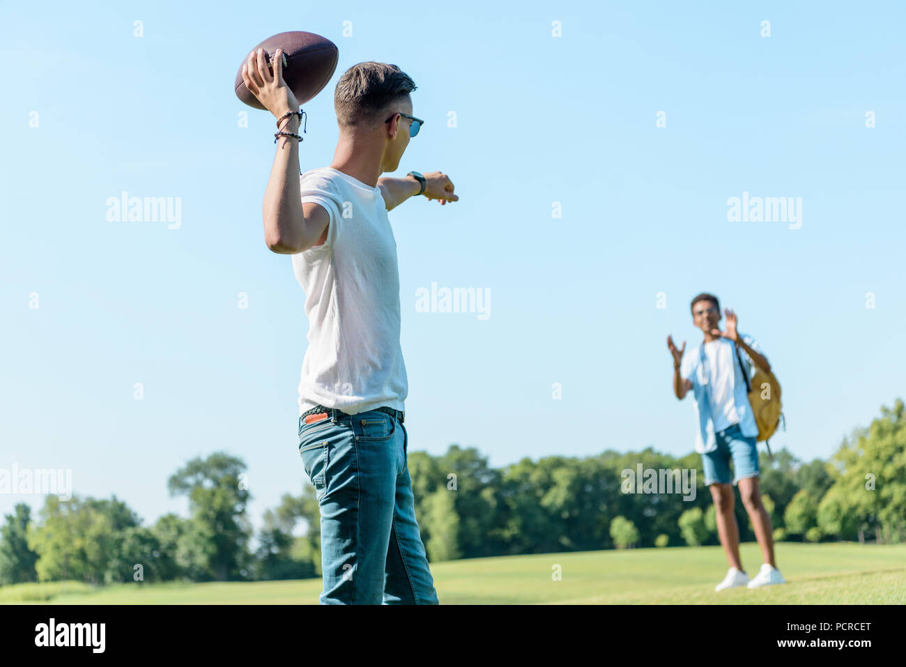 Adolescents multiethnique jouant avec ballon de rugby in park Banque D'Images