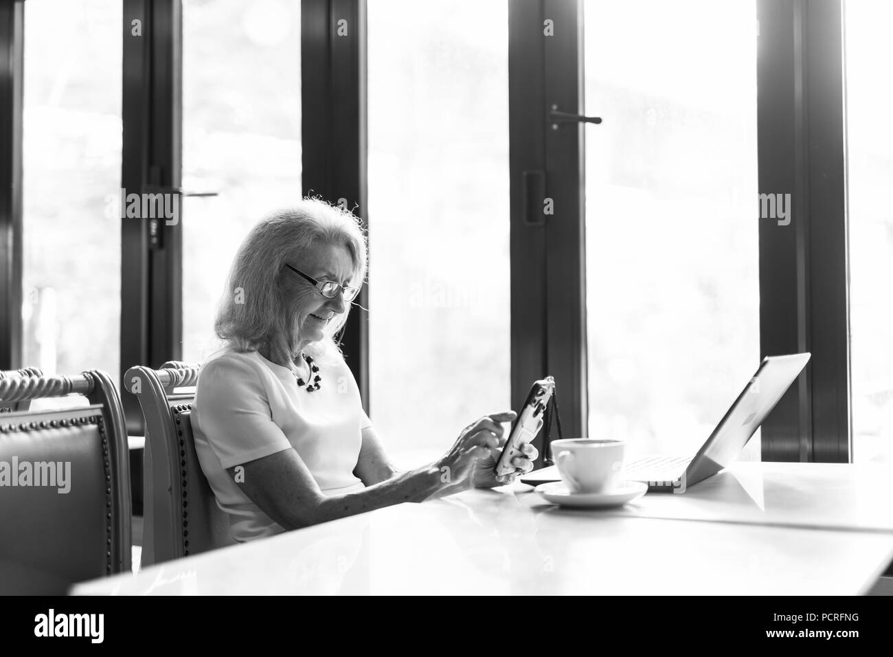 Senior Woman Using laptop computer and Mobile Phone Banque D'Images