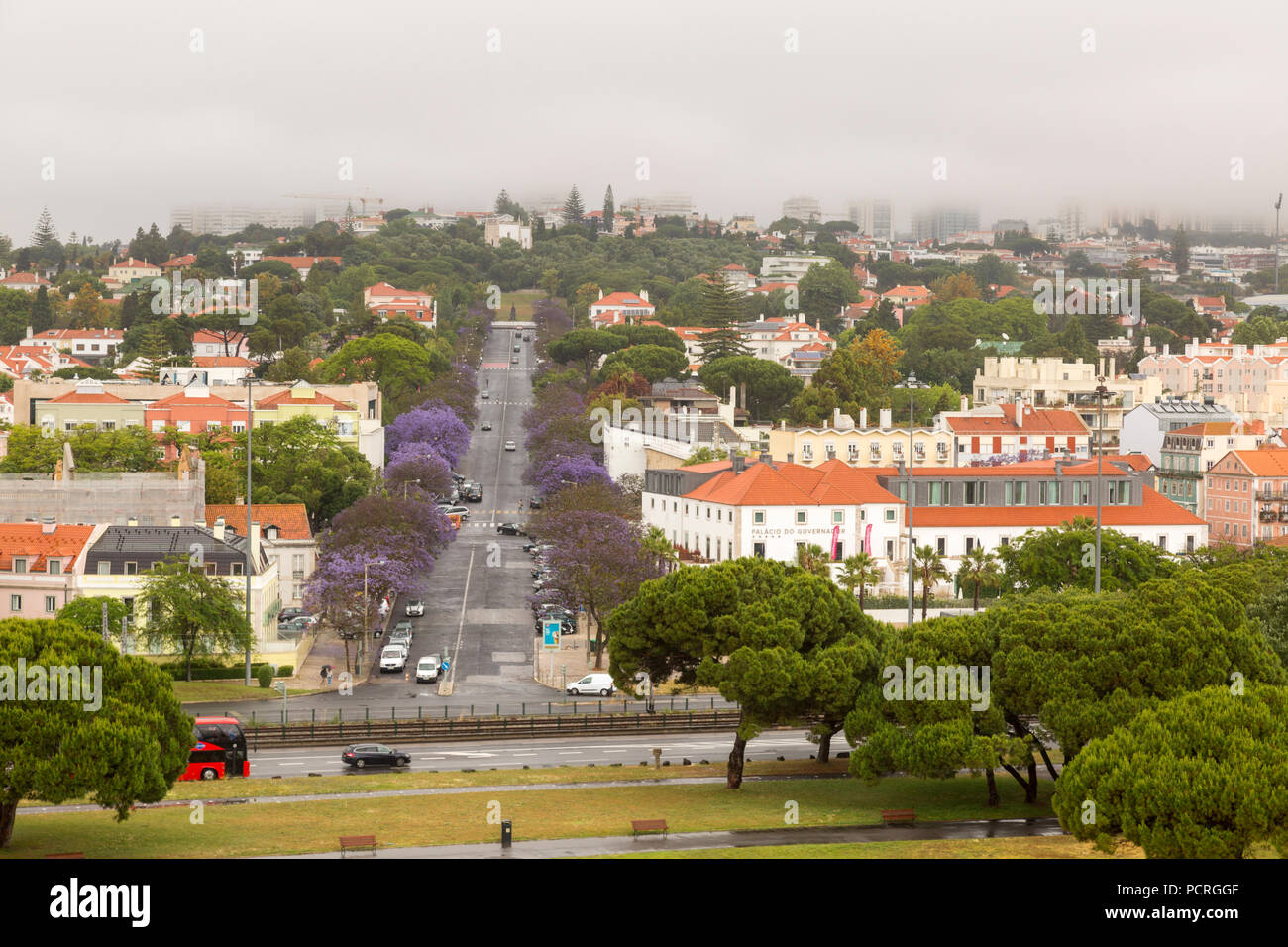 Vue de Lisbonne depuis le haut de la Tour de Belém. La rue est bordée de jacarandas en fleurs. Banque D'Images