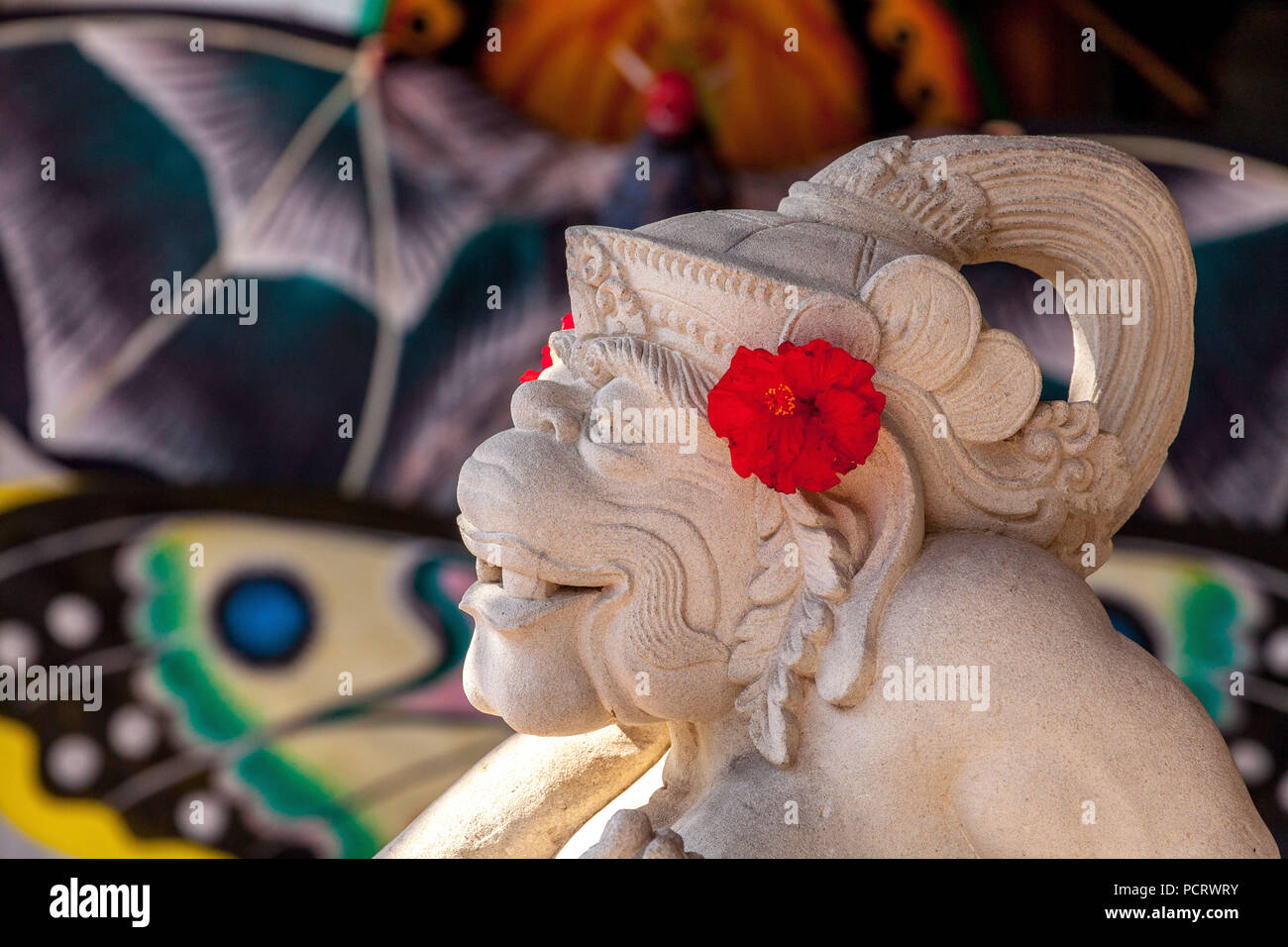 Dieu Singe Hanuman sculpté de pierre avec des fleurs d'hibiscus rouge, blanc calcaire, Hanuman, l'Hindouisme, hindoue, Ubud, Bali, Indonésie, Asie Banque D'Images