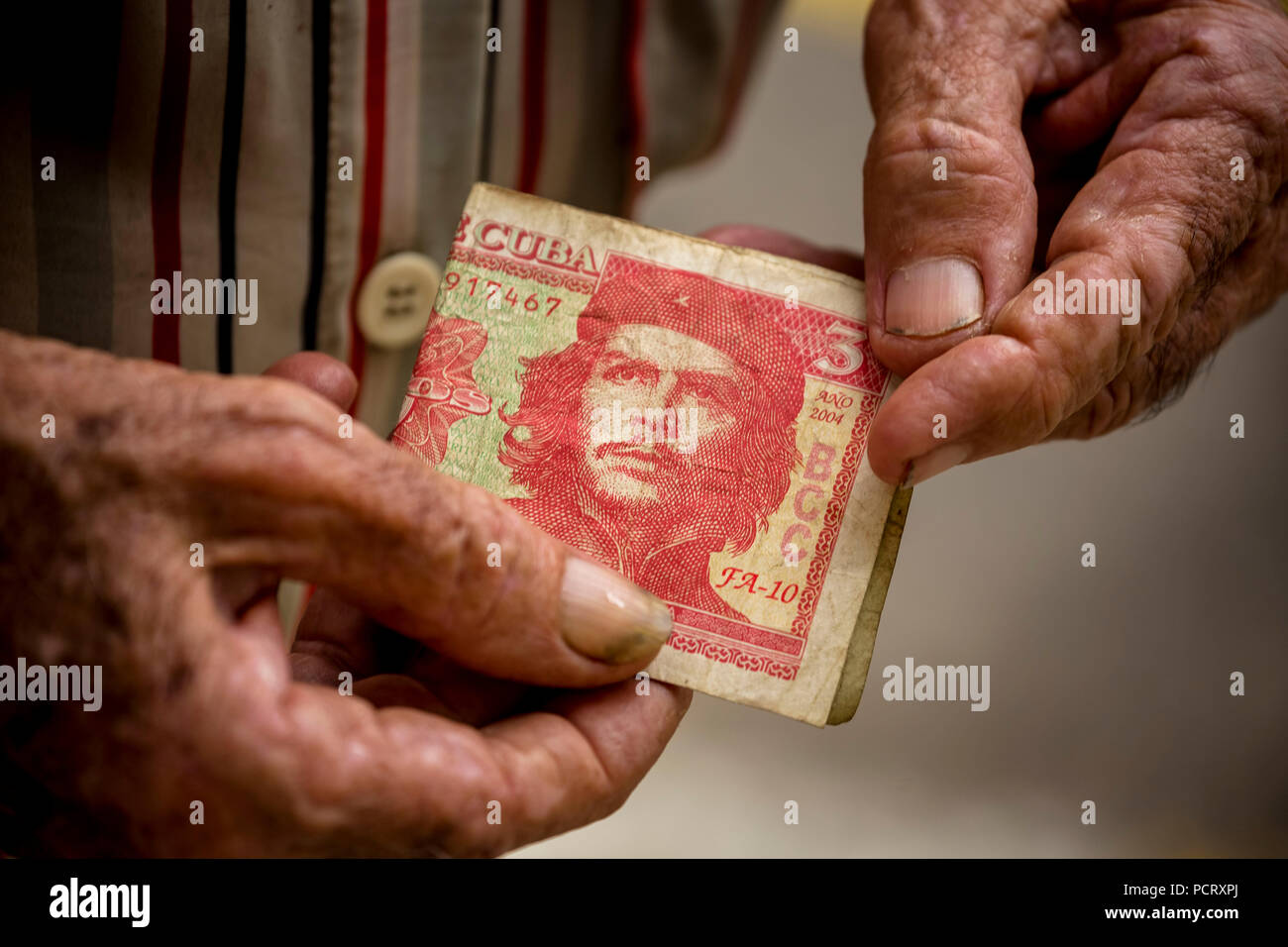 Vieux homme cubain détient un billet de 3 peso avec le portrait d'Ernesto Che Guevara dans la main, la monnaie locale, tasse, peso cubain, la pauvreté, La Habana, La Havane, La Havane, Cuba, Cuba Banque D'Images