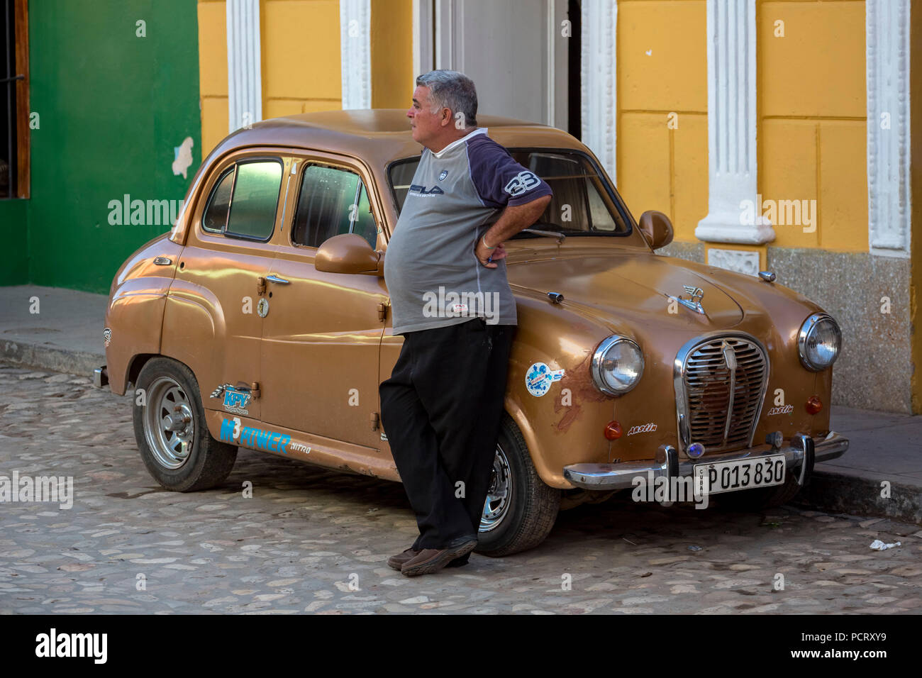 Fier propriétaire de voiture s'appuie contre sa petite voiture, Trinidad, Cuba, Holguín, Cuba Banque D'Images