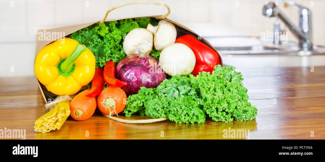 Les légumes biologiques frais de livraison des aliments en sac de papier sur banc en bois dans la cuisine Banque D'Images