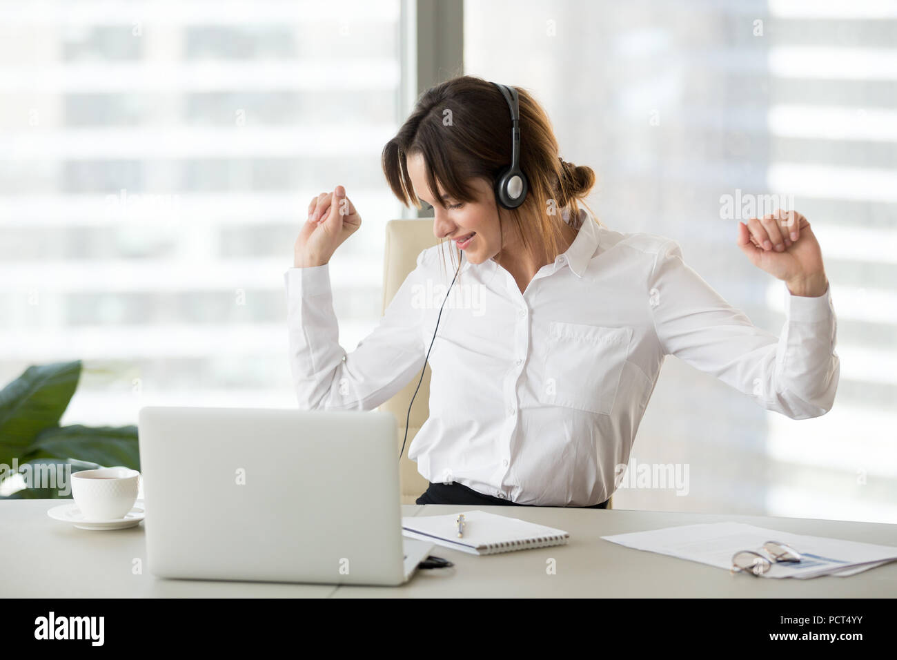 Les femmes au travail heureux d'écouter de la musique la danse de chaise de bureau Banque D'Images