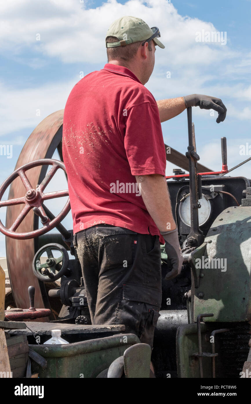 Un amateur de vapeur de la conduite sur le plancher d'un grand rouleau à vapeur d'époque ou de traction moteur à vapeur au rallye sur une journée d'été. Banque D'Images