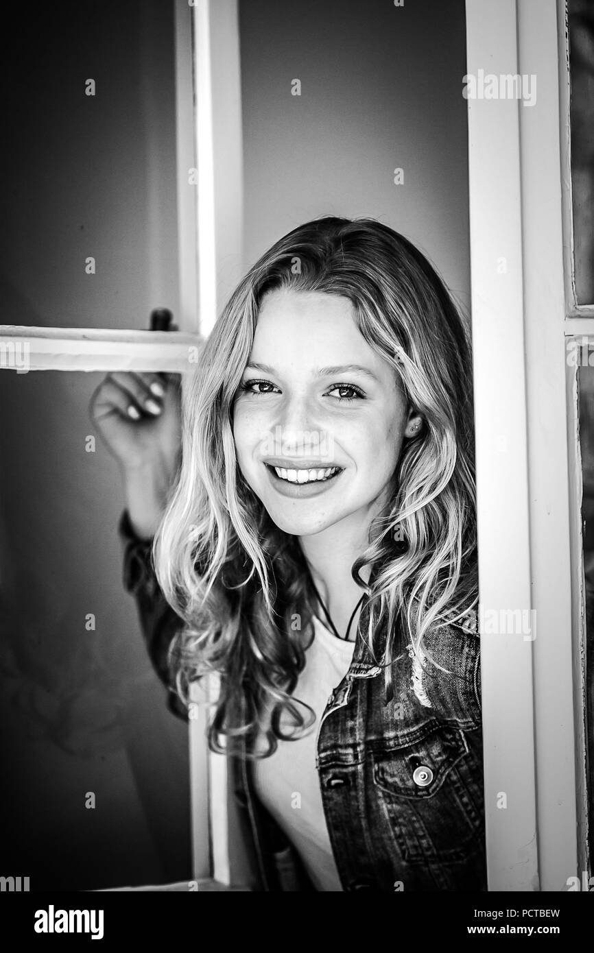 Jeune femme regardant par la fenêtre et rire à l'appareil photo Banque D'Images