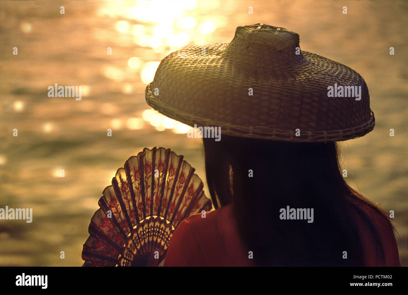 Femme Avec chapeau traditionnel hakka et ventilateur au coucher du soleil, de nouveaux territoires, à Hongkong, Chine Banque D'Images