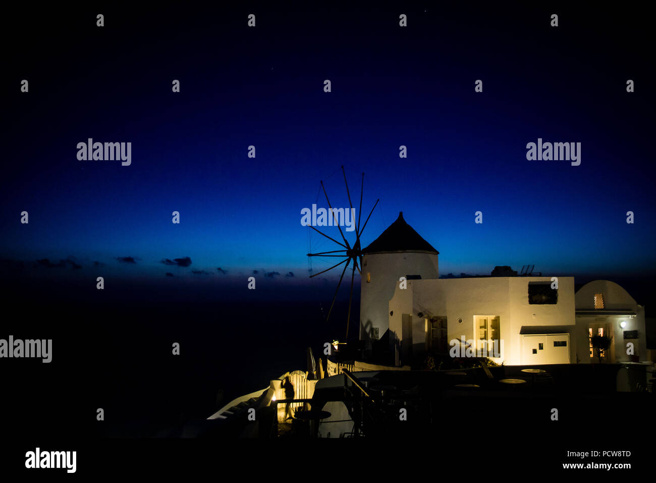 Traiditional moulin grec illuminée par l'éclairage artificiel pendant le coucher du soleil et l'heure bleue. Santorin, Grèce Banque D'Images