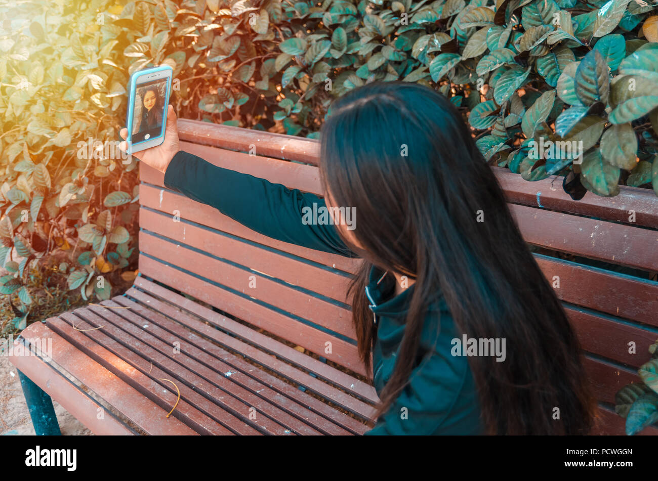 Jeune femme en tenant sur un banc selfies en utilisant son téléphone intelligent Banque D'Images