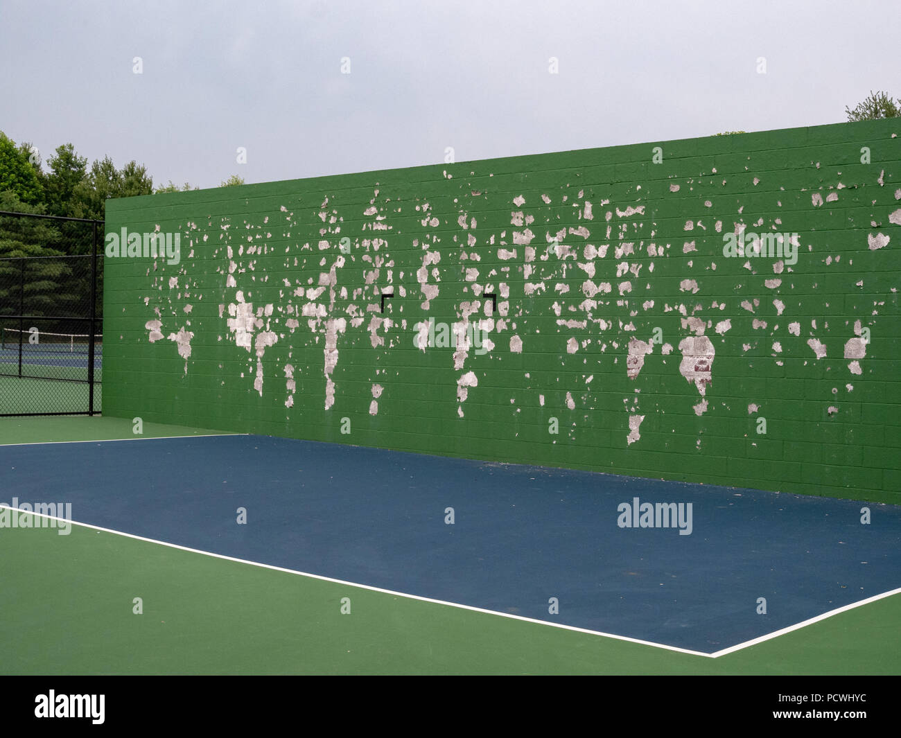 Le tennis, la crosse, la pratique sports de balle mur à un tribunal local avec décollement de peinture verte Banque D'Images