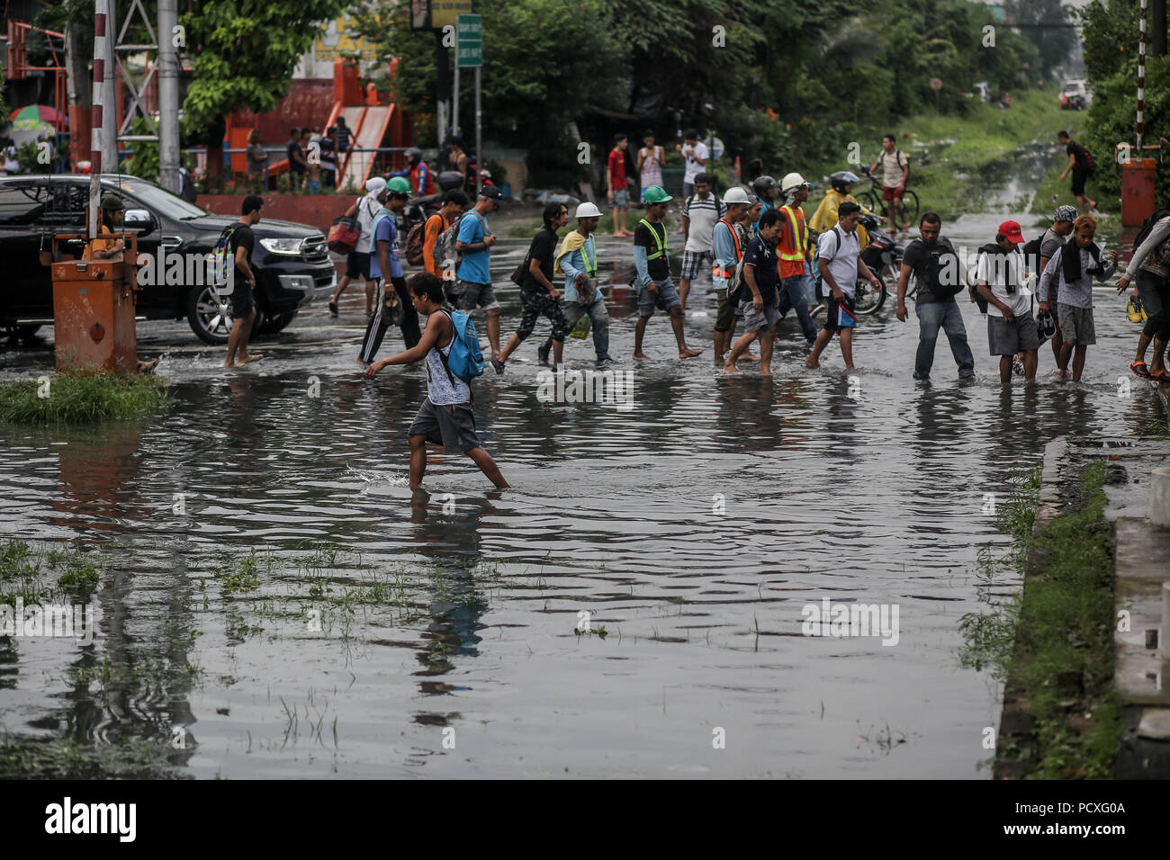 Manille, Philippines. 4 Août, 2018. Les gens traverser une voie ferrée inondée après une forte pluie à Manille, Philippines, le samedi. Le 4 août 2018. Les précipitations sont attendues dans certaines régions de Luzon et de la région métropolitaine de Manille en raison d'orages violents portés par la mousson du sud-ouest. Credit : Basilio Sepe/ZUMA/Alamy Fil Live News Banque D'Images
