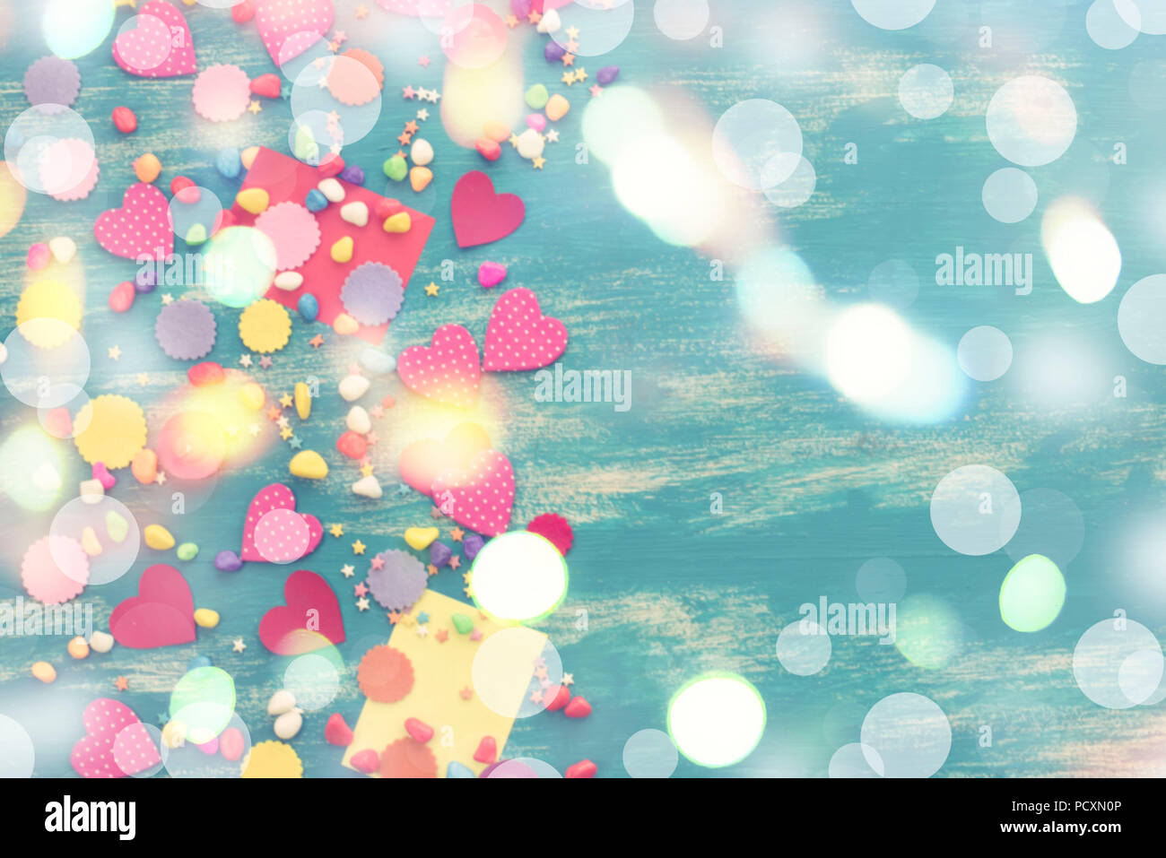 Confettis de fête de flou artistique en arrière-plan couleur bonbons coeur saturé. Vieux bois fond bleu avec copie espace télévision lay Banque D'Images