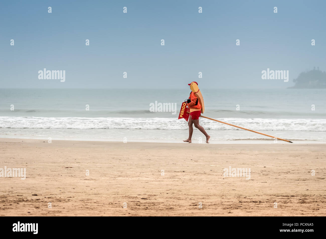 Life guard marche sur la plage par une journée ensoleillée Banque D'Images