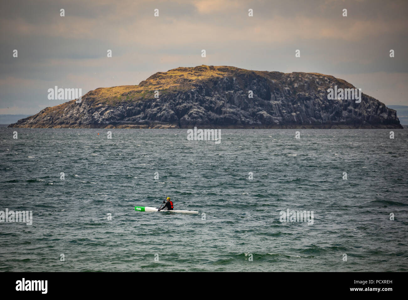 Kayakiste de mer solitaire passe une île au large de North Berwick, East Lothian, Scotland Banque D'Images