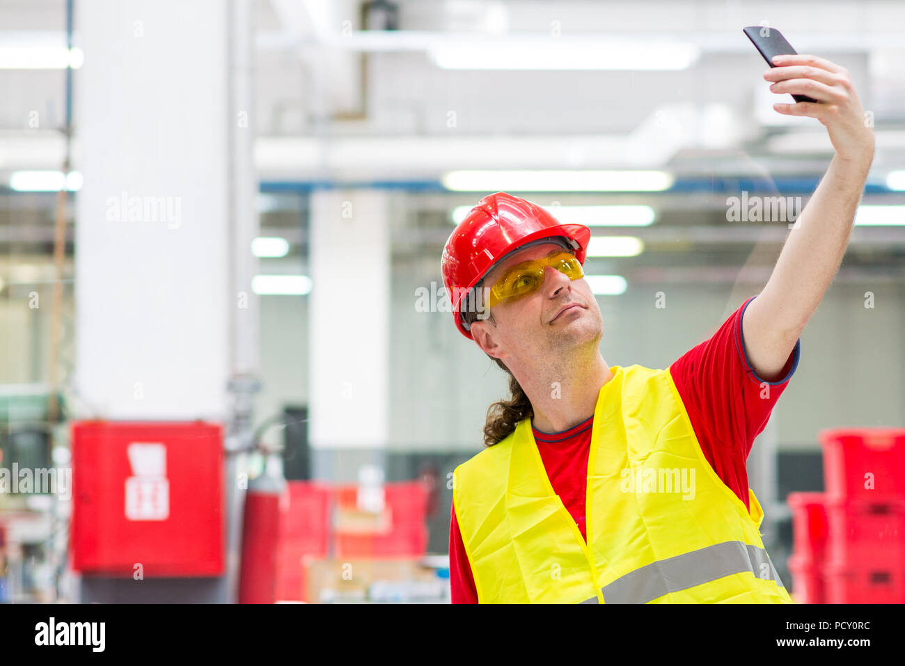 Travailleur de l'usine en tenant dans une usine selfies Banque D'Images