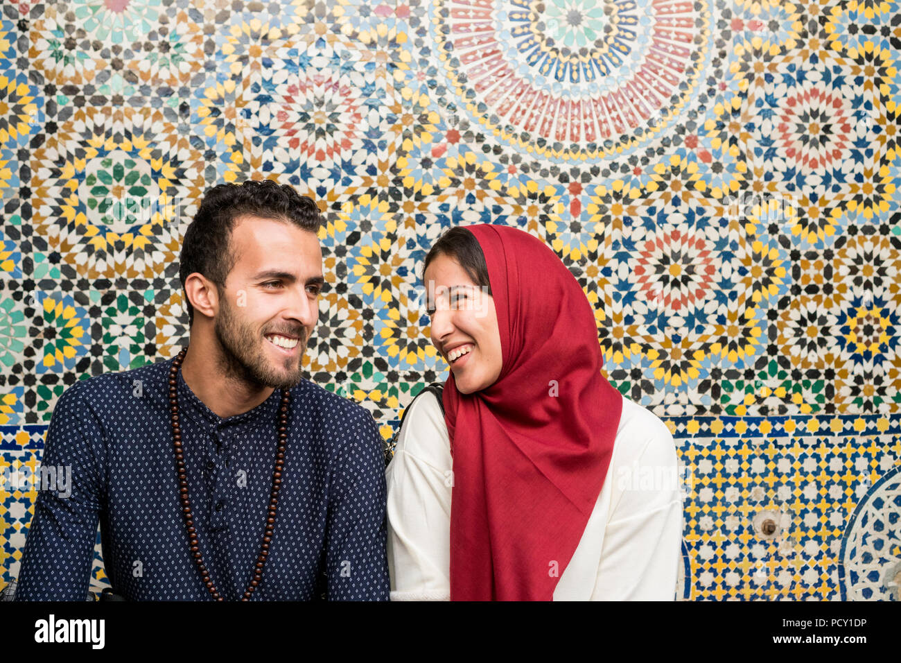 Les jeunes couples musulmans par rapport à parler et souriant en face d'arabesque décoration orientale Banque D'Images