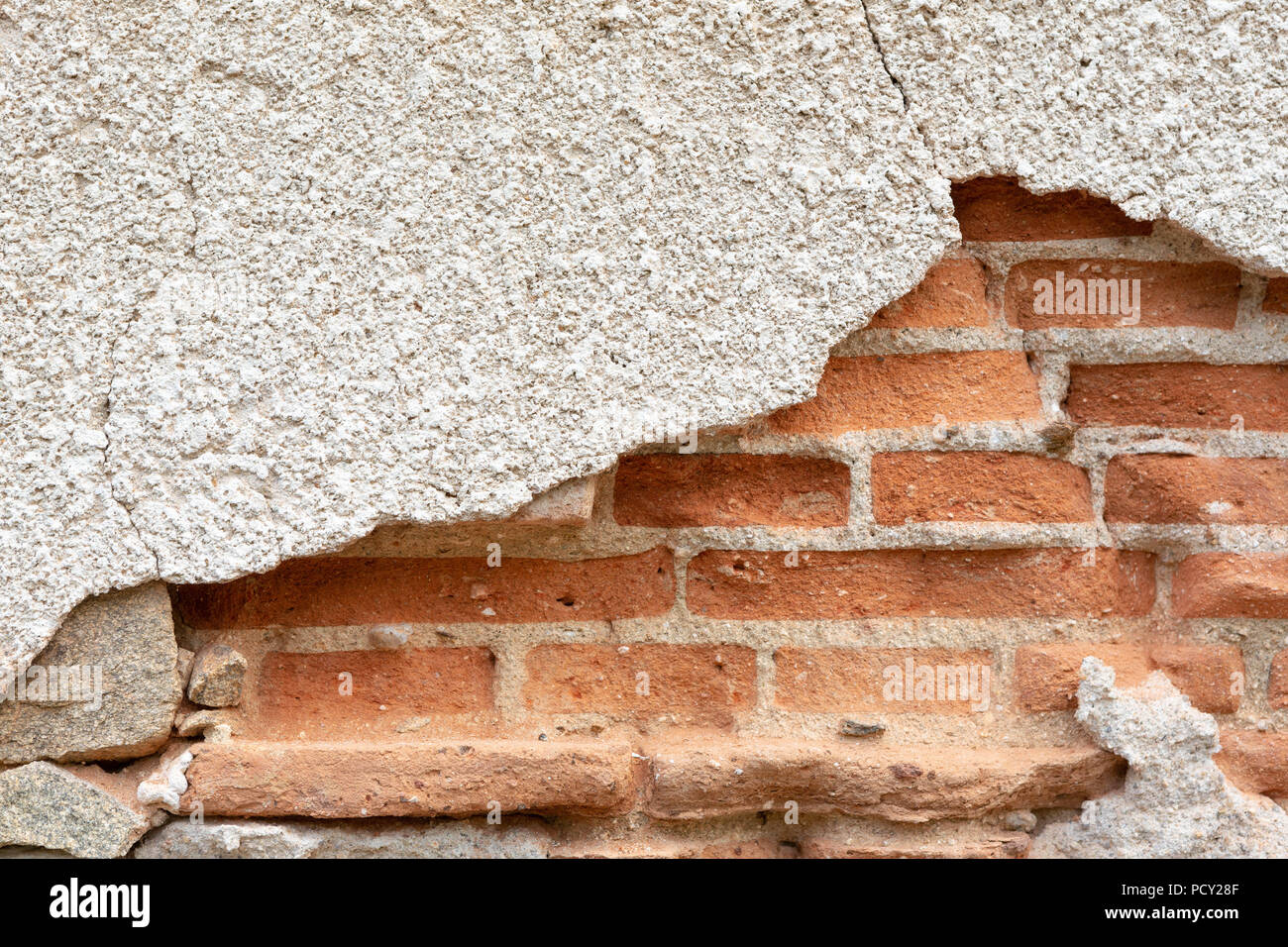 Vieux plâtre endommagé sur un mur de brique rouge. Banque D'Images