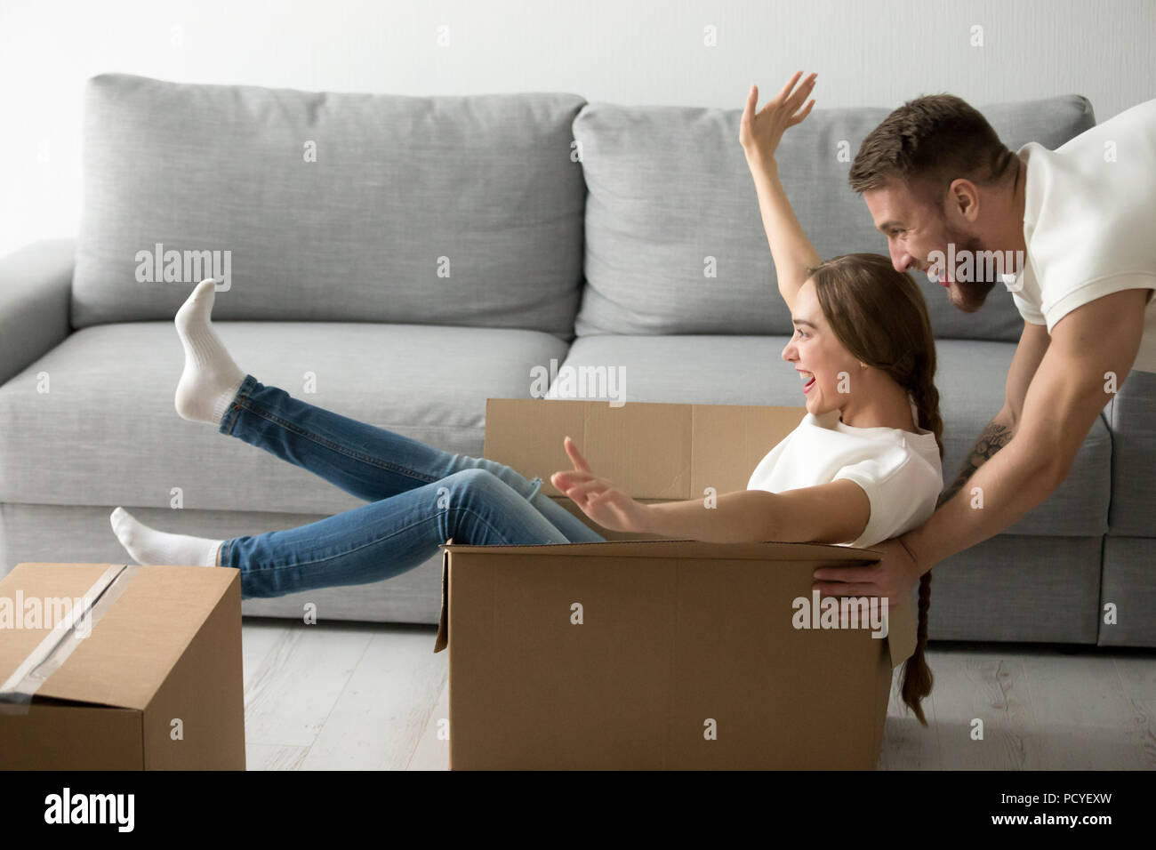 Heureux couple riding dans les cases s'amusant unpacking boxes Banque D'Images