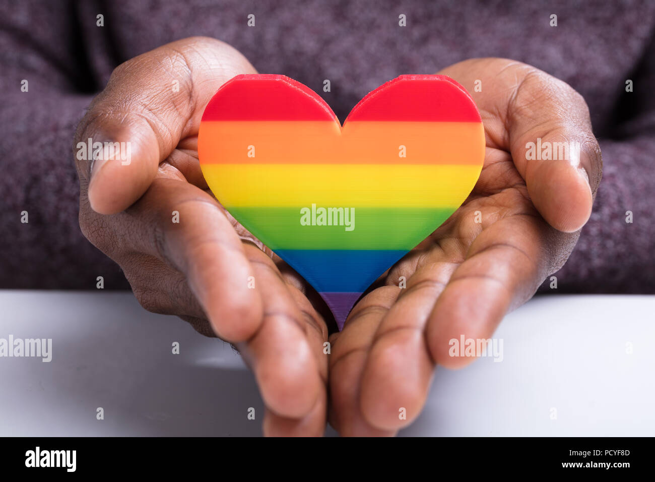 Close-up of Man's Hand Holding coeur peint à rayures colorées Banque D'Images