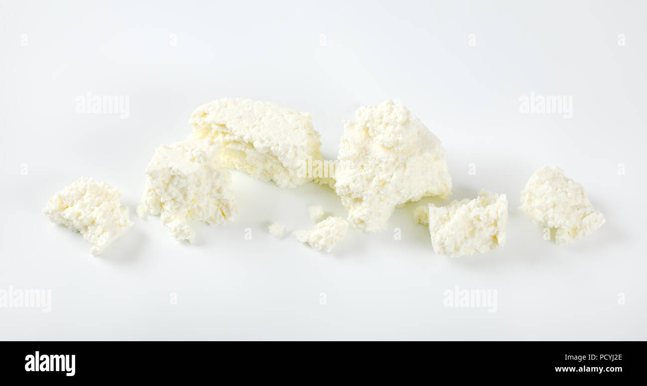 Morceaux de fromage blanc friable sur fond blanc Banque D'Images
