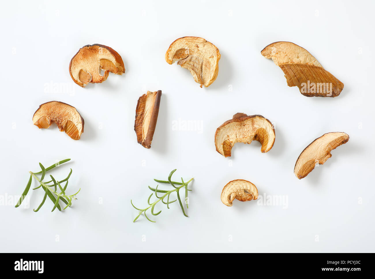 Tranches de champignons séchés et de romarin sur fond blanc Banque D'Images
