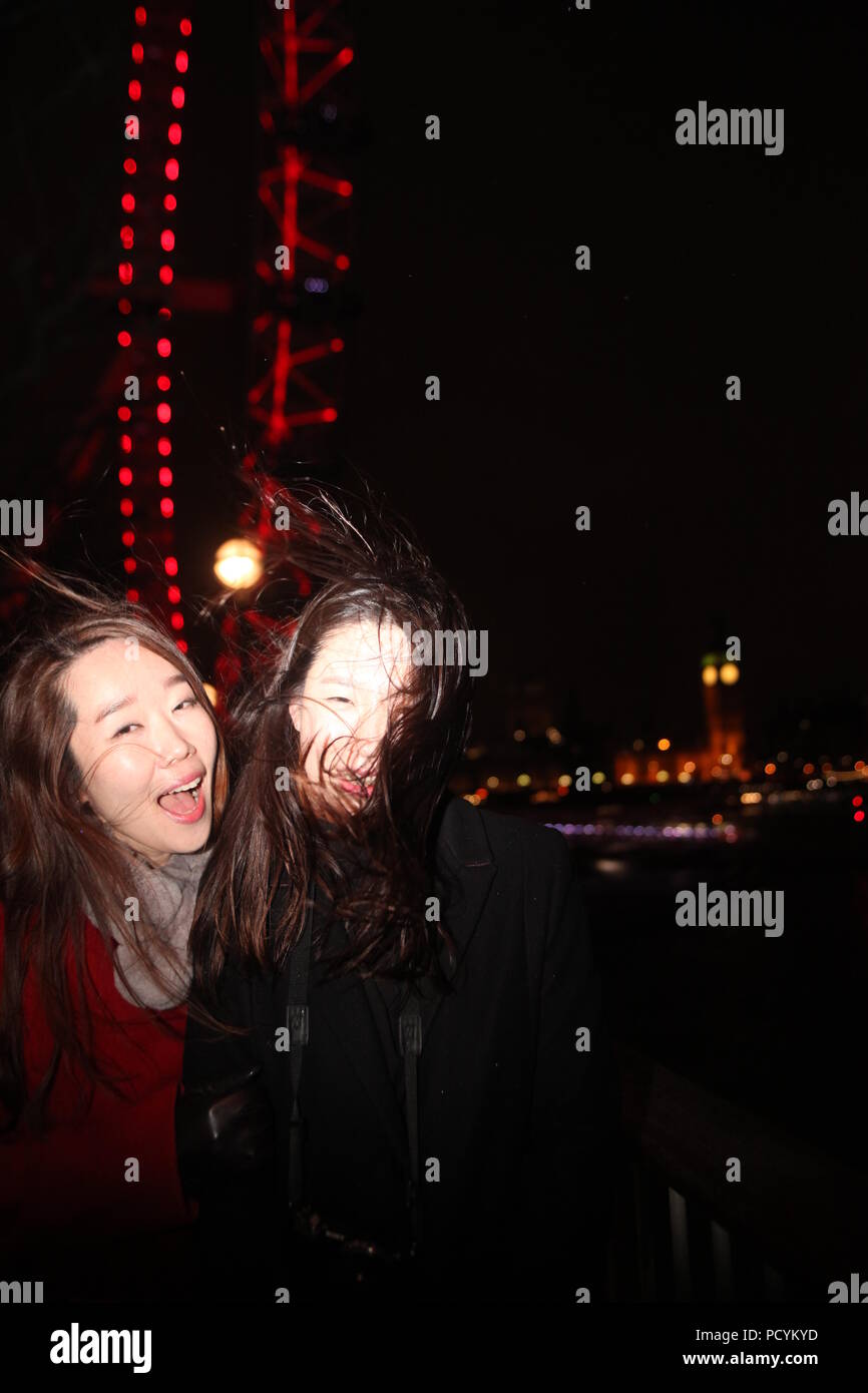 Deux jeunes étudiants coréen mesdames profitez de l'hiver le soir pendant leur visite à Londres, photo avec Big Ben et London Eye lights en arrière-plan Banque D'Images