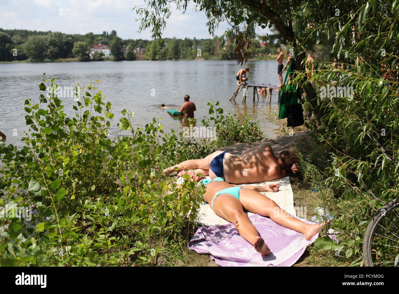 Jeune femme ukrainienne et l'homme reste sur les bords du lac à Kiev profiter de l'été agréable de soleil tandis que d'autres gens sur le poisson et la plage s'amuser Banque D'Images