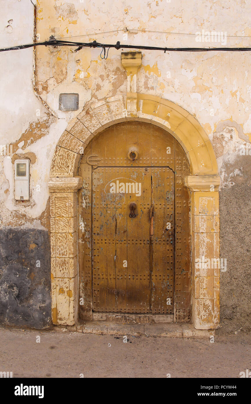 Des tons jaunes de la trame d'une porte en bois. Pièces Jaunes restants de la couleur sur la façade de la maison. Street à El Jadida, Maroc. Banque D'Images