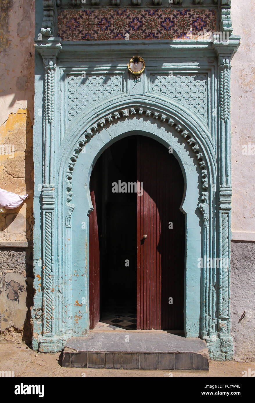 Barrière en bois peint en bleu clair avec de nombreux détails. Brown la moitié a ouvert la porte. Journée ensoleillée. Street à El Jadida, Maroc. Banque D'Images
