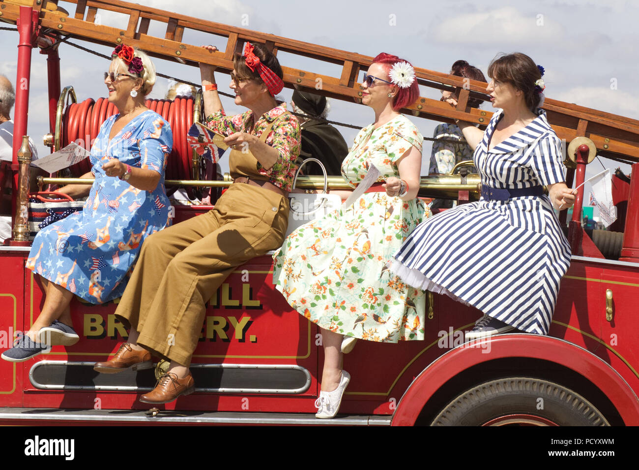 Les femmes vêtus de vêtements des années 40, assis sur un moteur de feu guerre vintage Banque D'Images