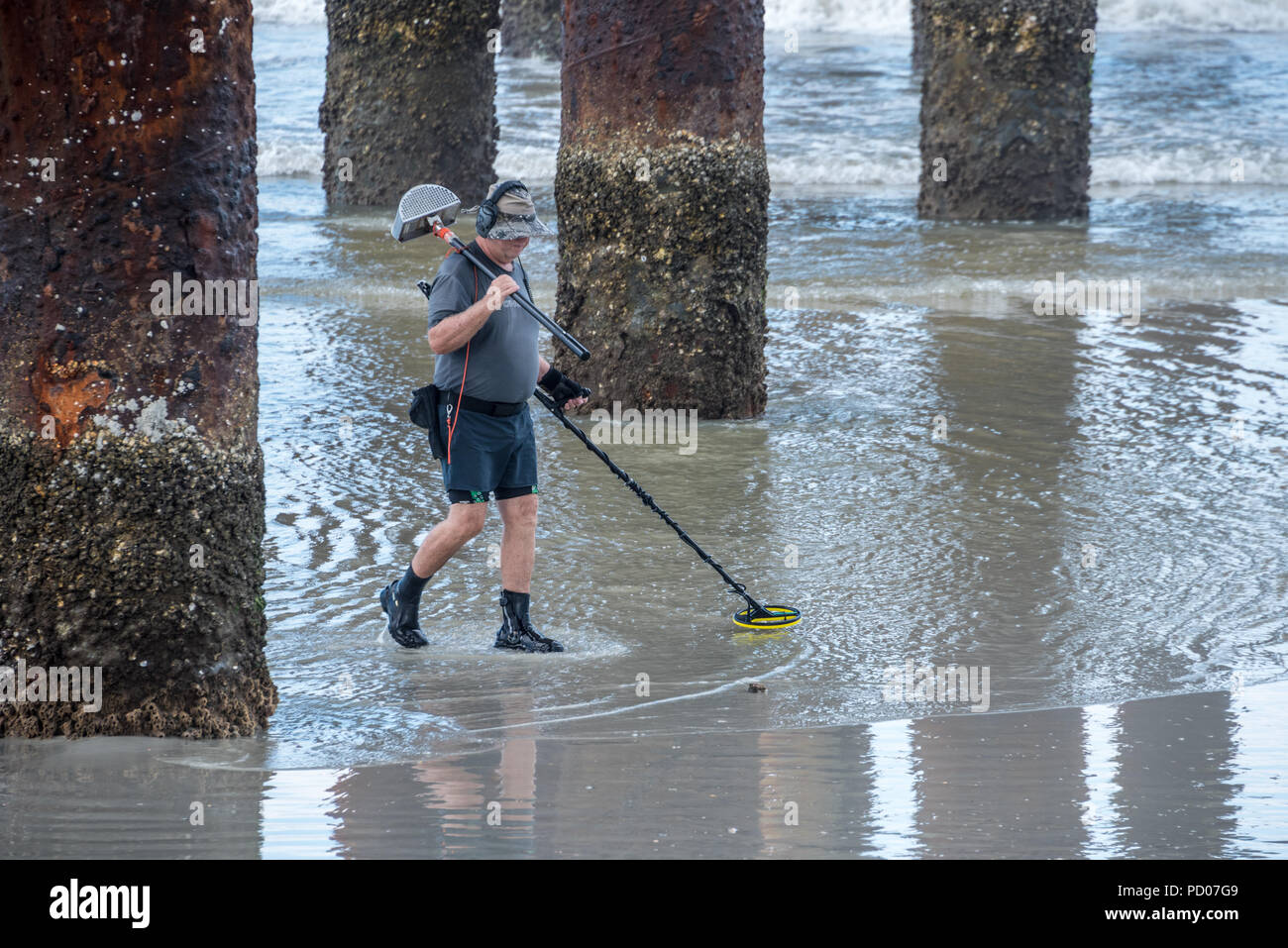 Homme avec détecteur de métal sous le comté de Saint John's Ocean Pier à Saint Augustine Beach, en Floride. (USA) Banque D'Images