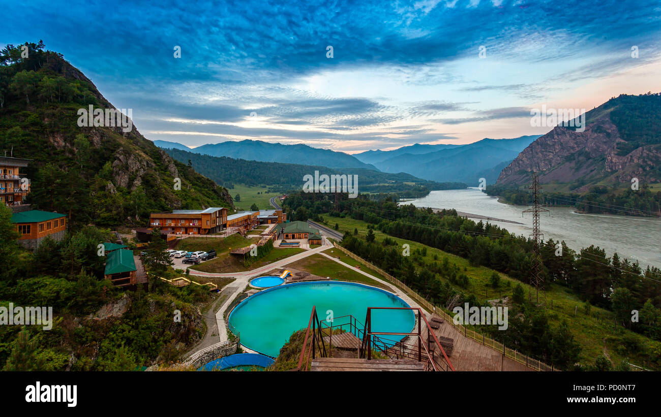 Panorama de montagne : un petit village, d'un centre de loisirs avec une piscine et de petites maisons en bois dans les montagnes de l'Altaï, près d'une rivière de montagne et route Banque D'Images