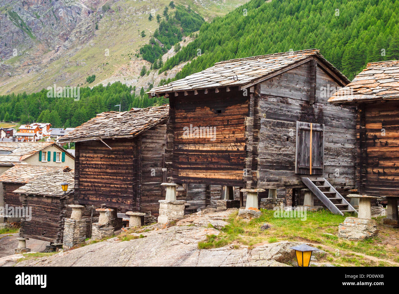 Toit en ardoise traditionnelle huttes de bois sur staddle pierres à l'entrée dans le village de Saas Fee Saastal (Vallée de Saas), canton du Valais, Suisse Banque D'Images