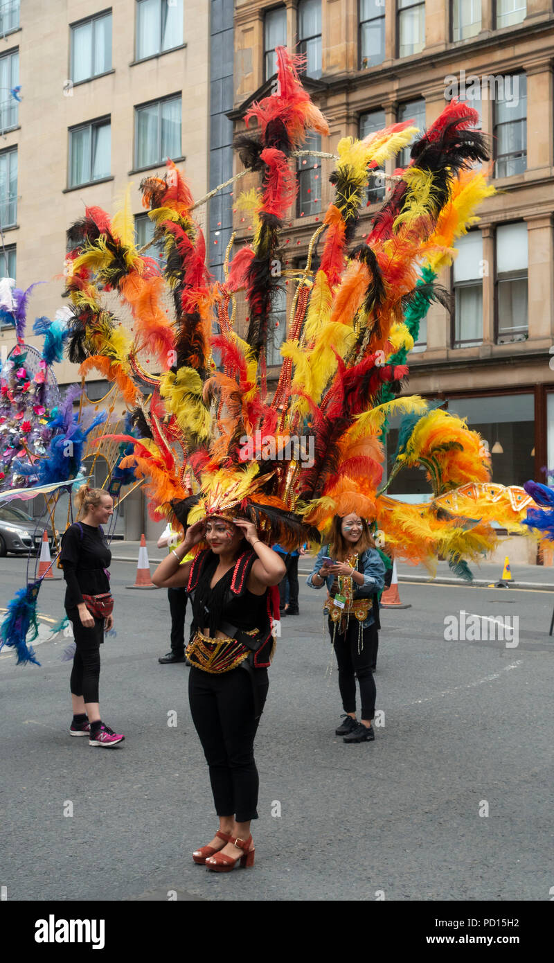 Femme flamboyand et ajustant son couvre-chef en plumes colorés juste avant le début du carnaval Procession de la Merchant City Festival : 2018 Banque D'Images