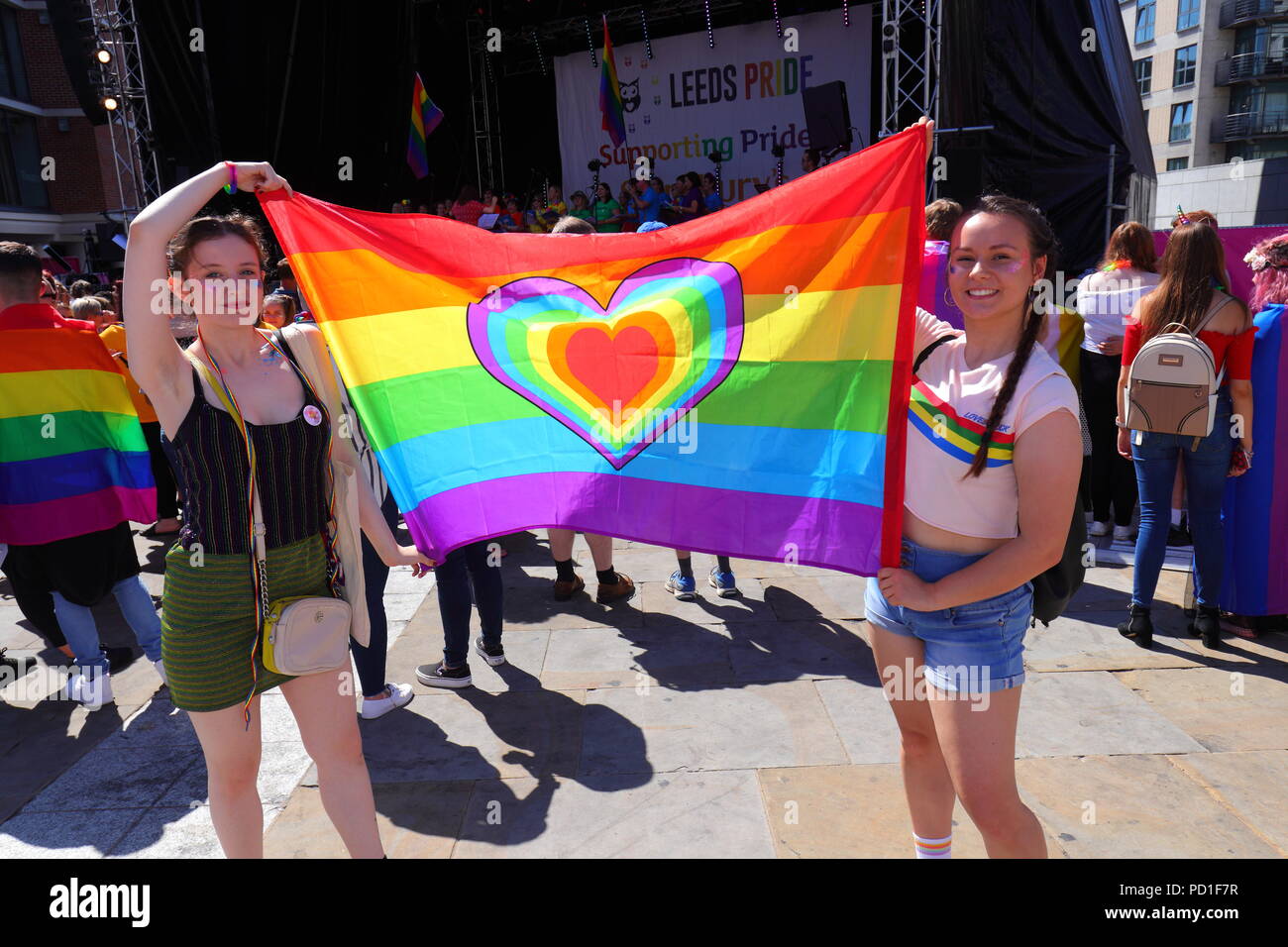 2 filles posent avec un drapeau LGBT au cours de l'événement Pride LGBT de Leeds à Millennium Square dans le centre-ville de Leeds Banque D'Images
