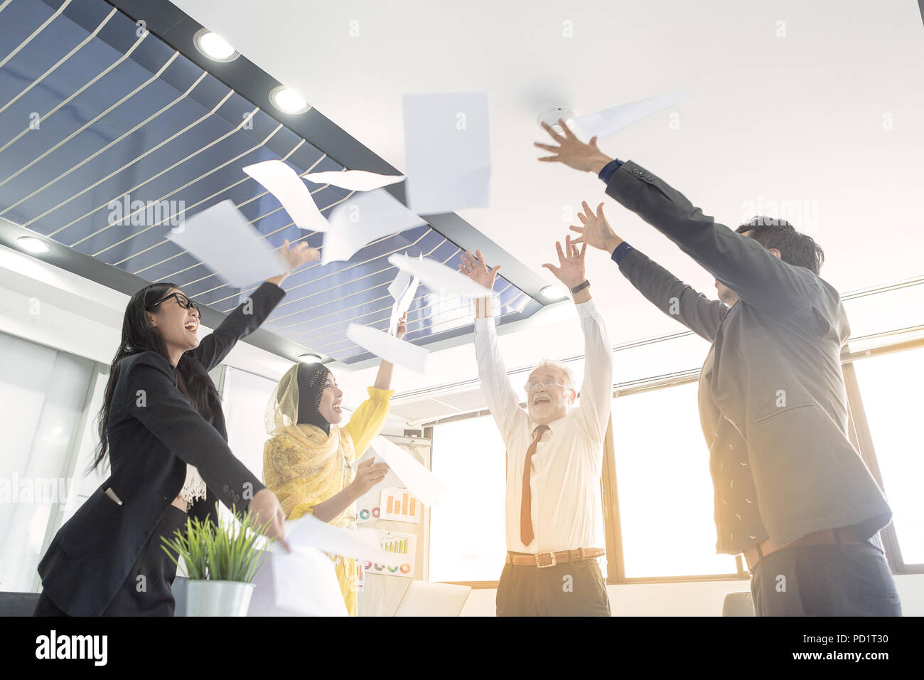 Les gens d'affaires d'équipe jeter Papiers et documents, voler dans l'air alors que heureux sourire heureux. Concept de l'équipe de succès après avoir signer un contrat ou terminé la Banque D'Images