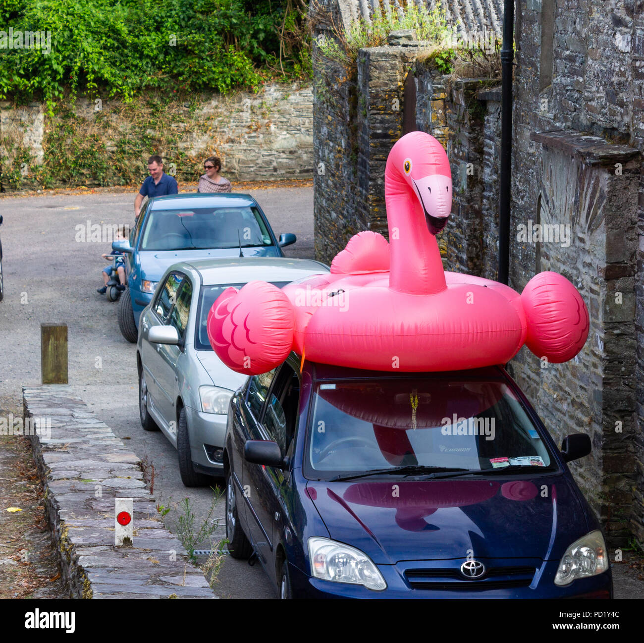 Ballon de plage en plastique gonflable d'un flamand rose sur un toit de voiture. Banque D'Images