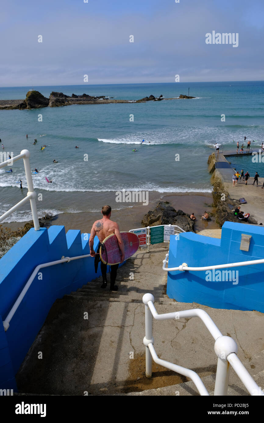 Bude, Cornwall, UK. Surfer promenades vers Bude semi-naturels du bassin de baignade de la mer Banque D'Images
