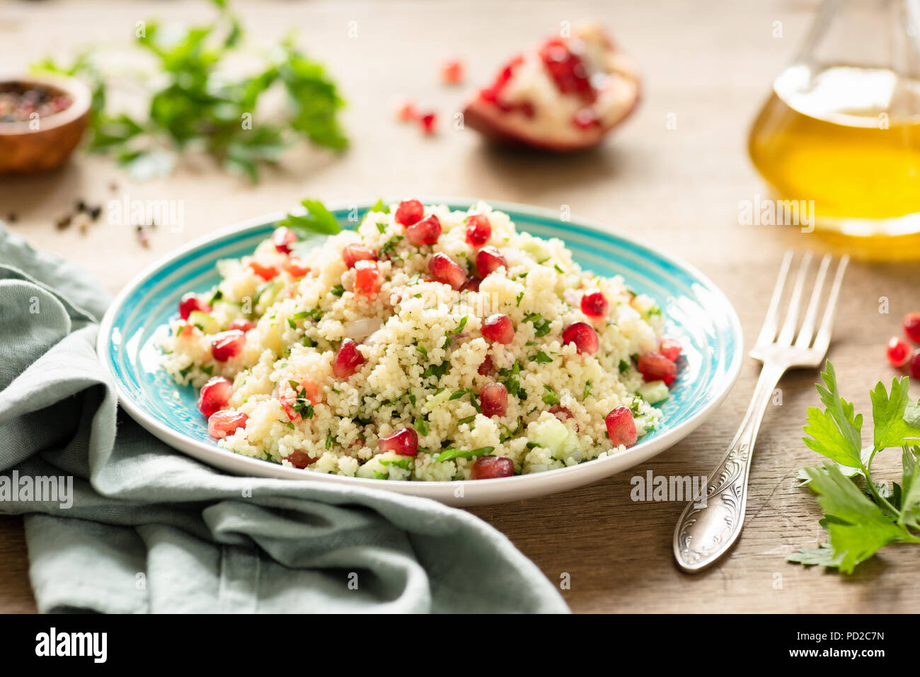 Taboulé, salade de couscous moyen-orientale à la grenade, le persil, le concombre sur plaque turquoise authentique. Repas végétarien Banque D'Images